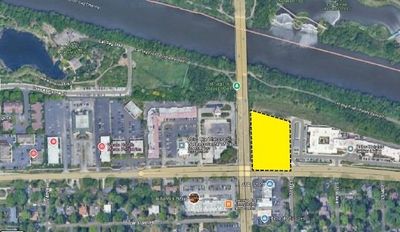 Aerial view, highway crossing a river, retail stores and a yellow highlighted lot.