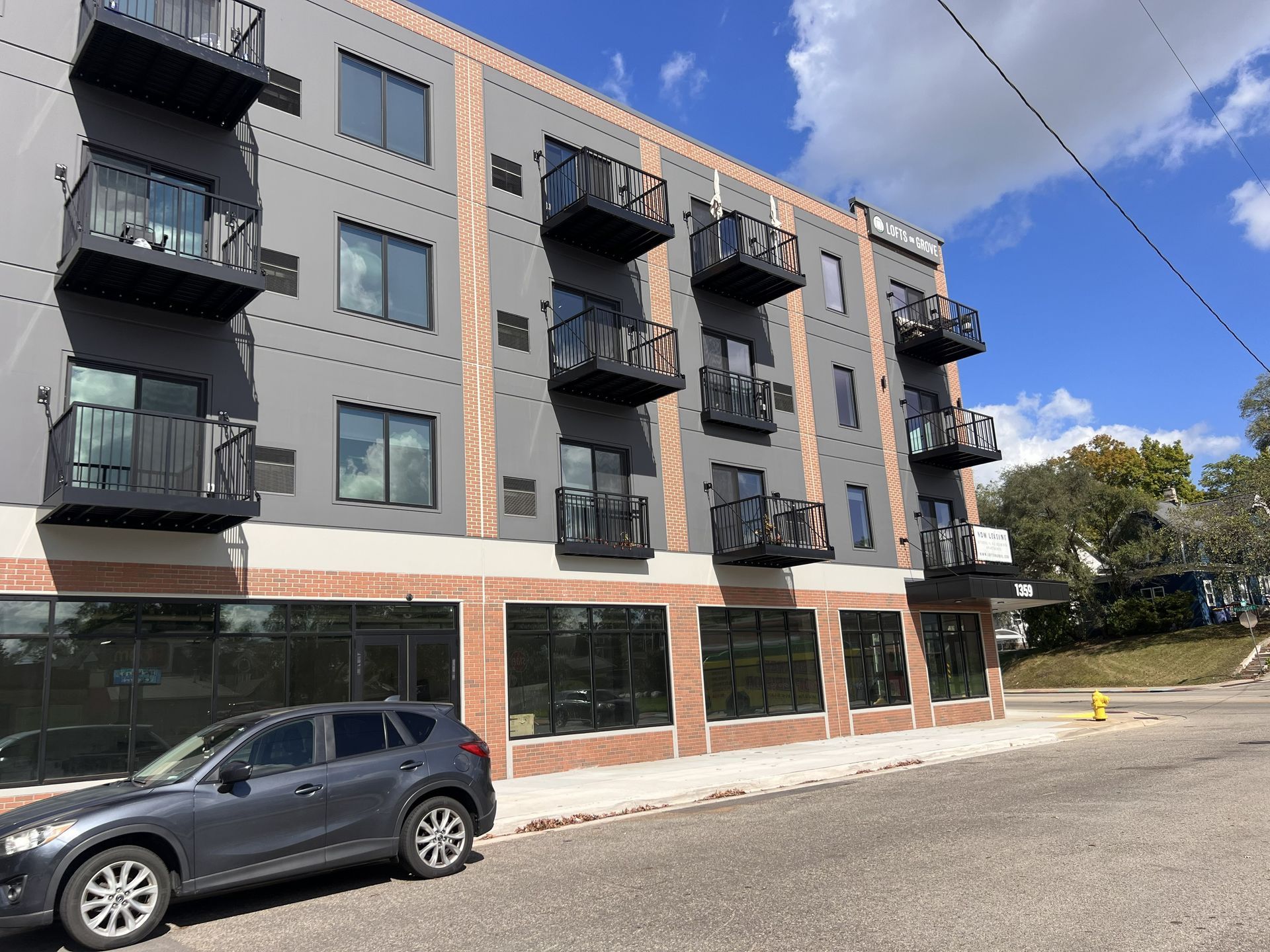 Modern apartment building with balconies and a parked car on a quiet street