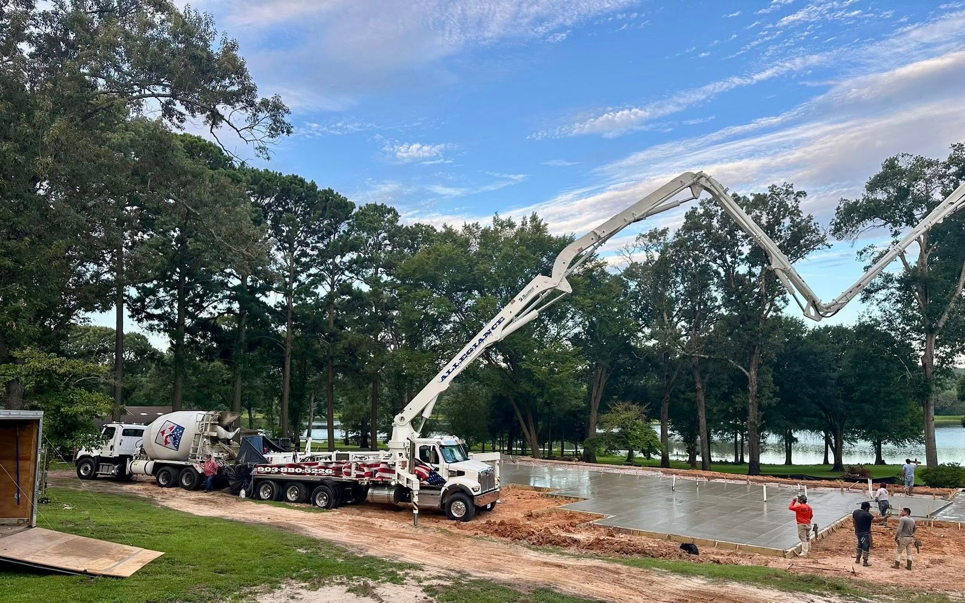 A concrete pump truck is being used to pump concrete into a pond.