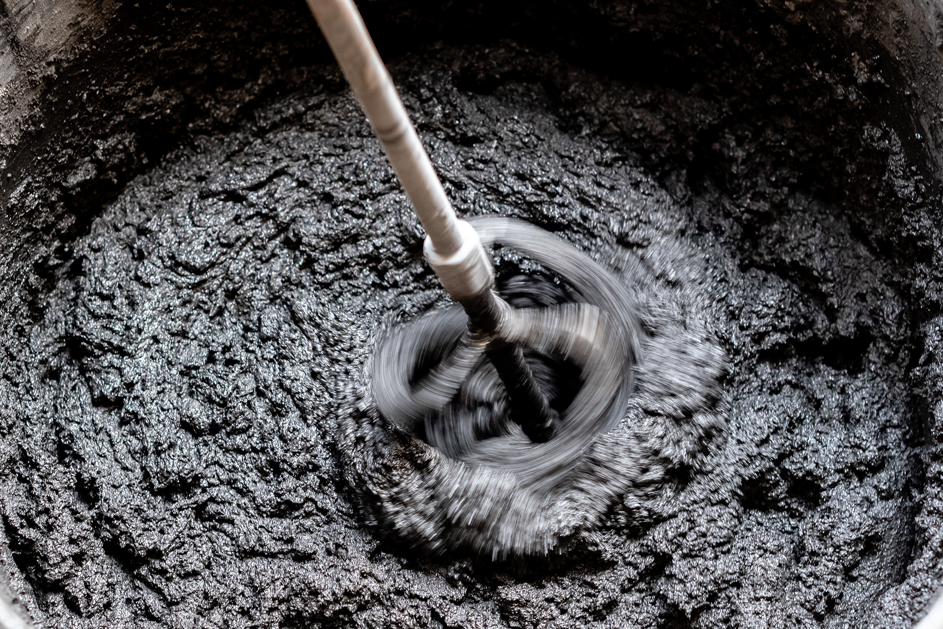 A mixer is mixing a black substance in a bowl.