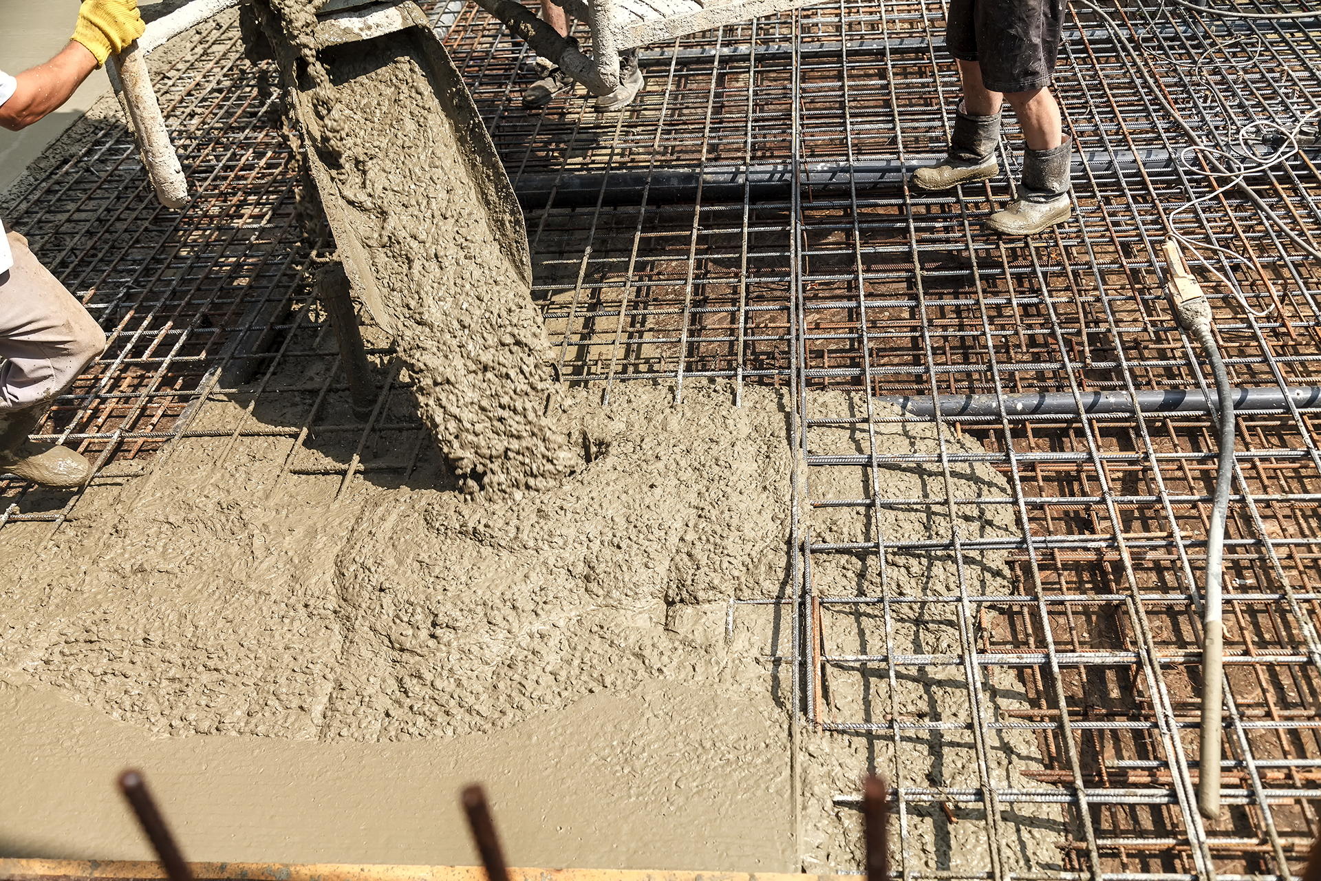 A man is pouring concrete into a steel structure.