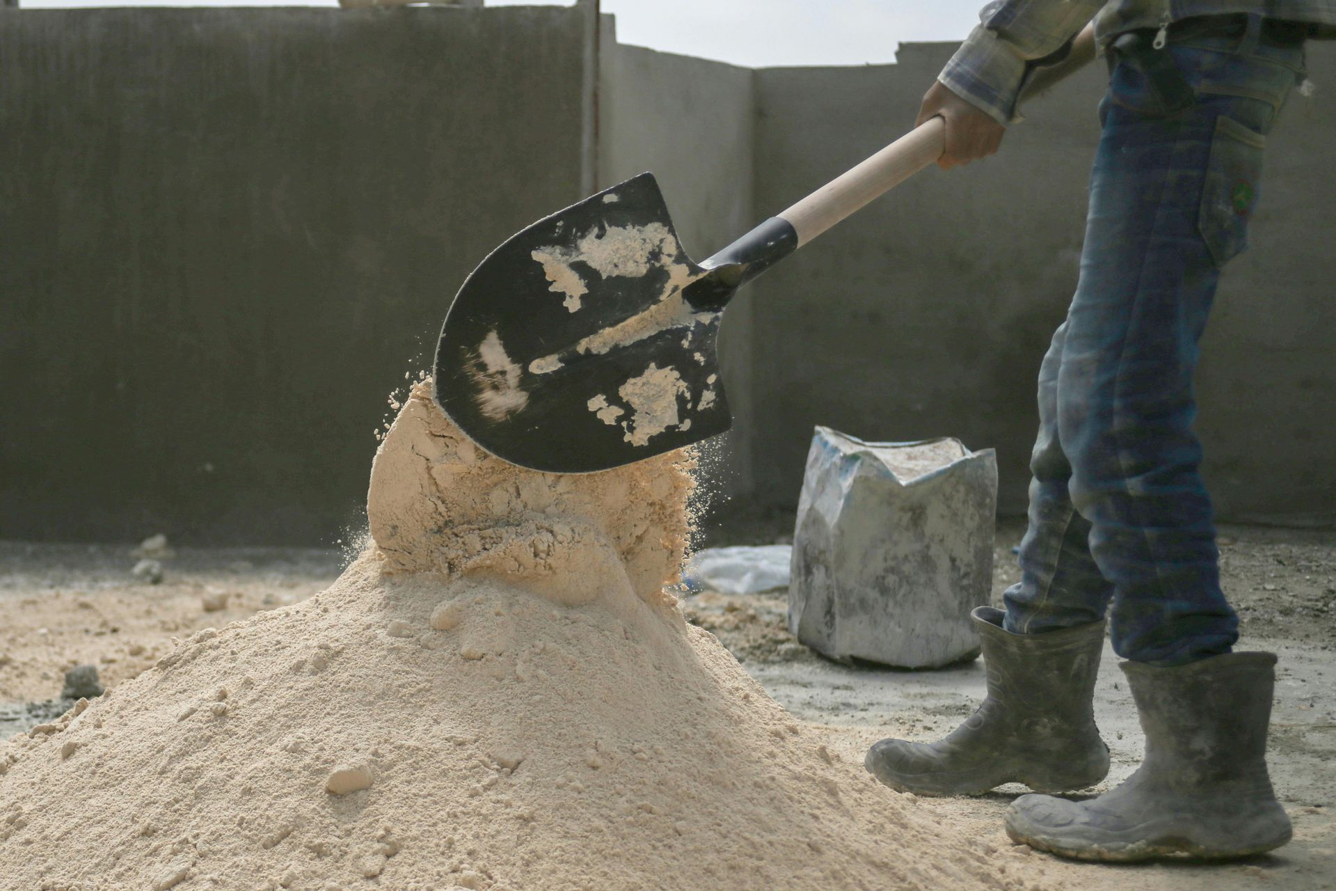 A person is pouring sand into a pile with a shovel