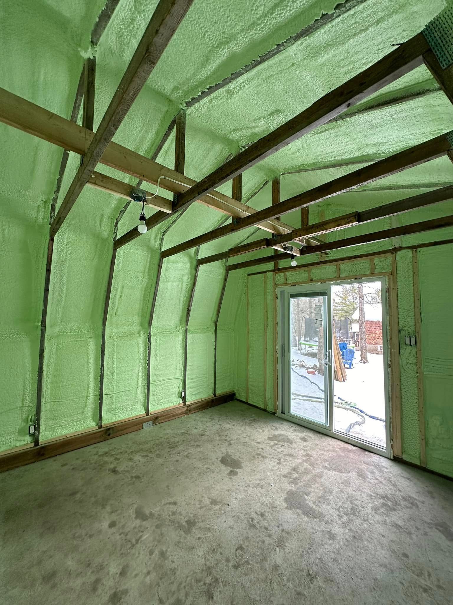 An empty room with green spray foam on the walls and ceiling.