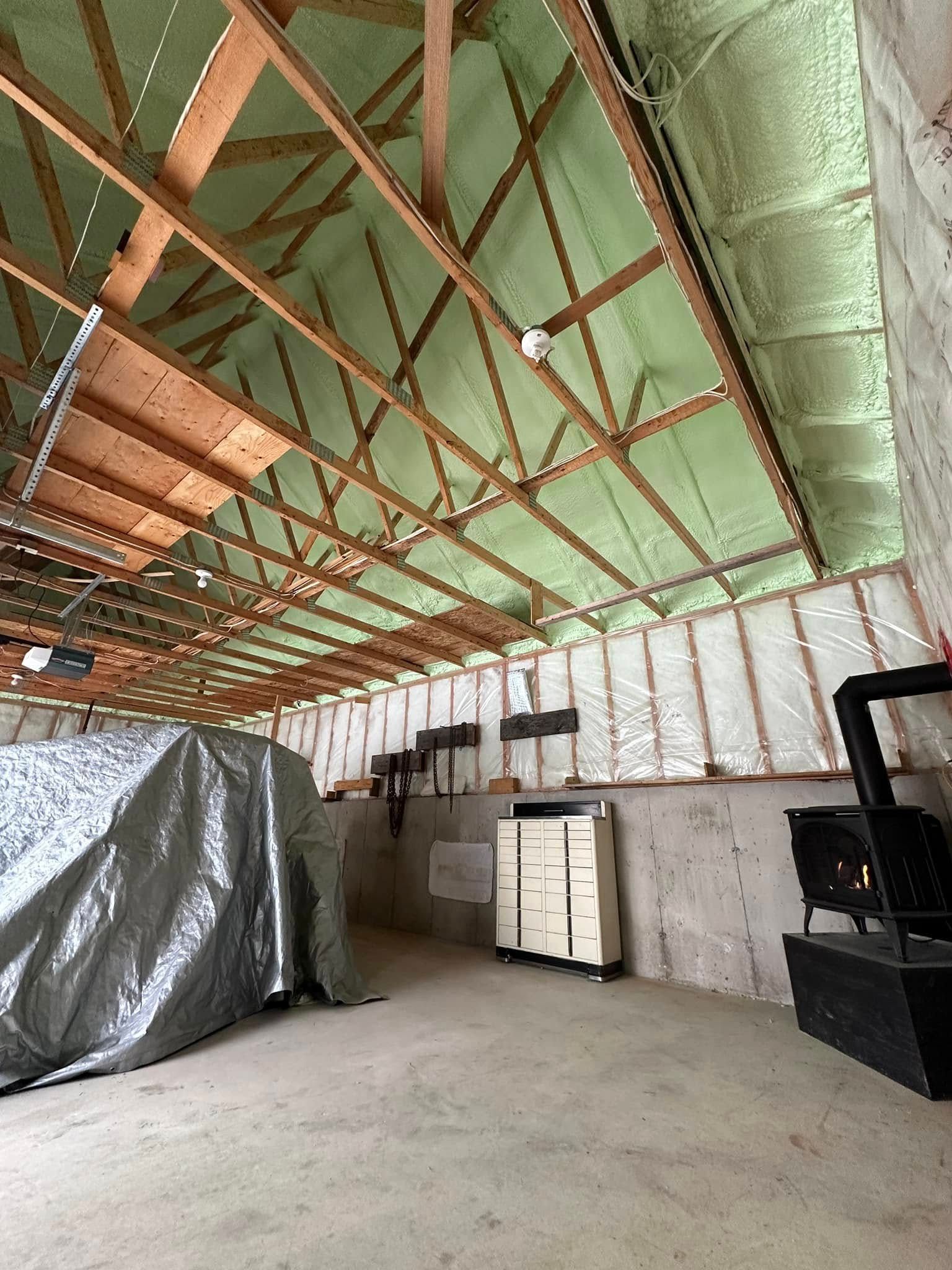 A garage with green spray foam insulation and a wood stove.