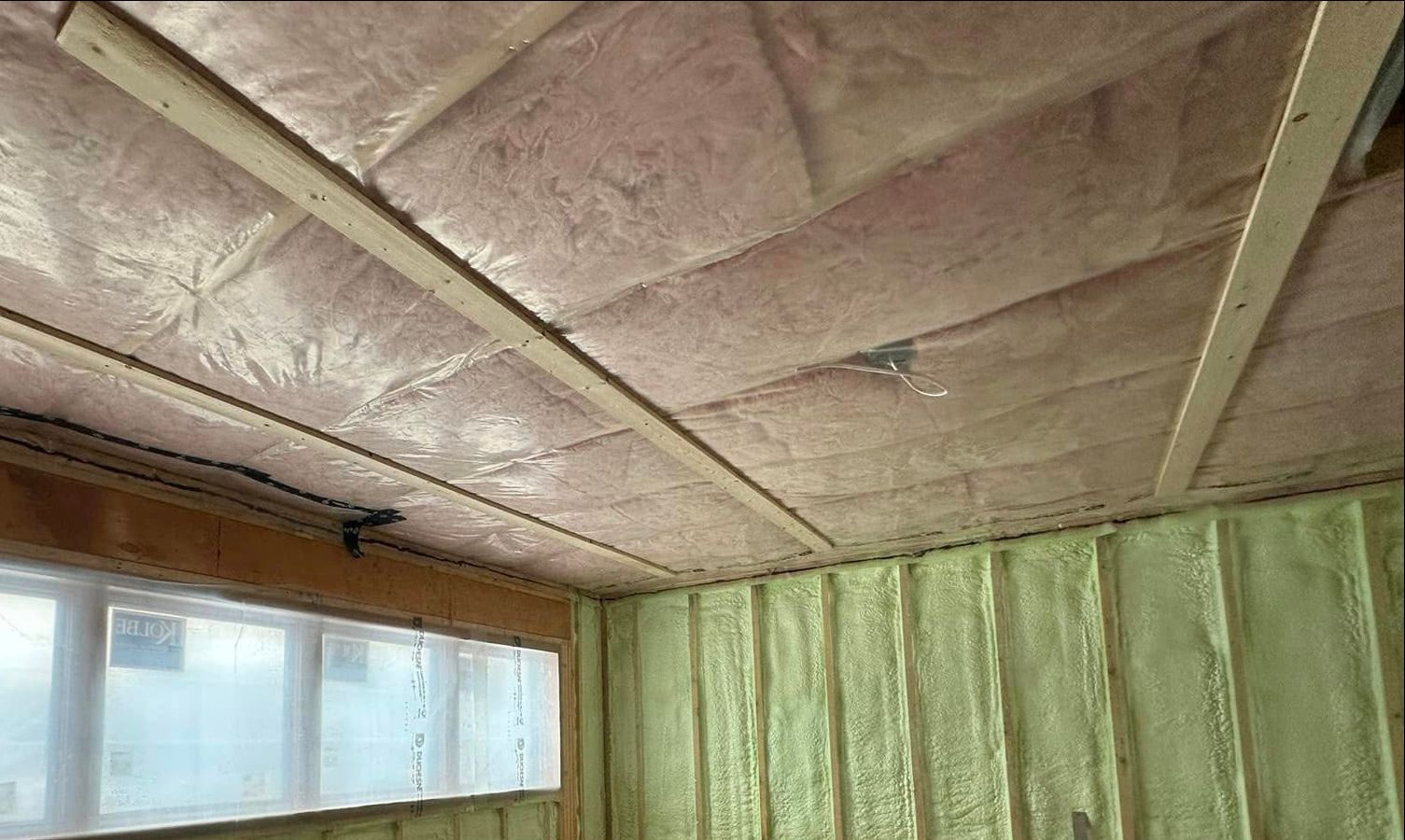 A room with a ceiling covered in insulation and a window.