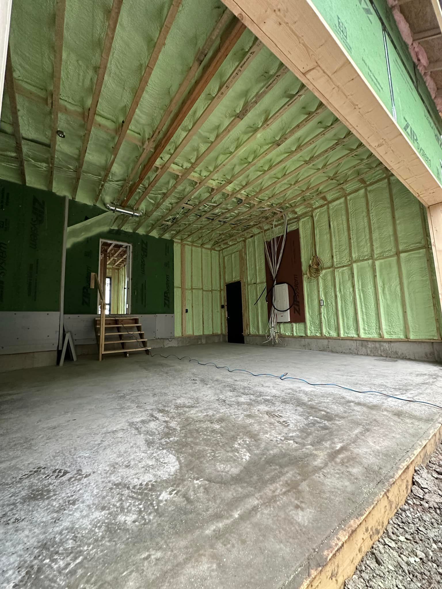 A large empty room with a concrete floor and a green ceiling.
