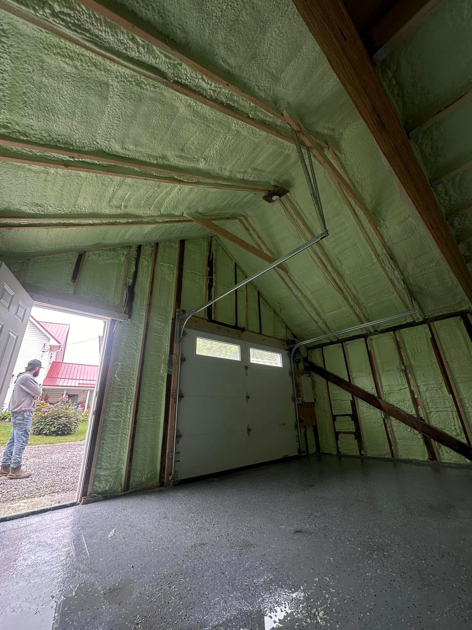 A man is standing in a garage with a garage door open.