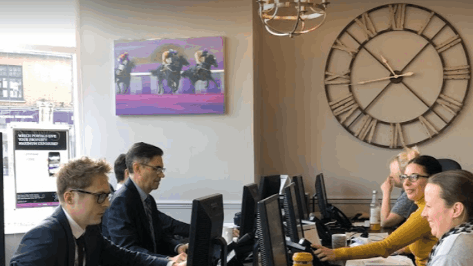 A group of people are sitting at desks in front of computer monitors in an office.