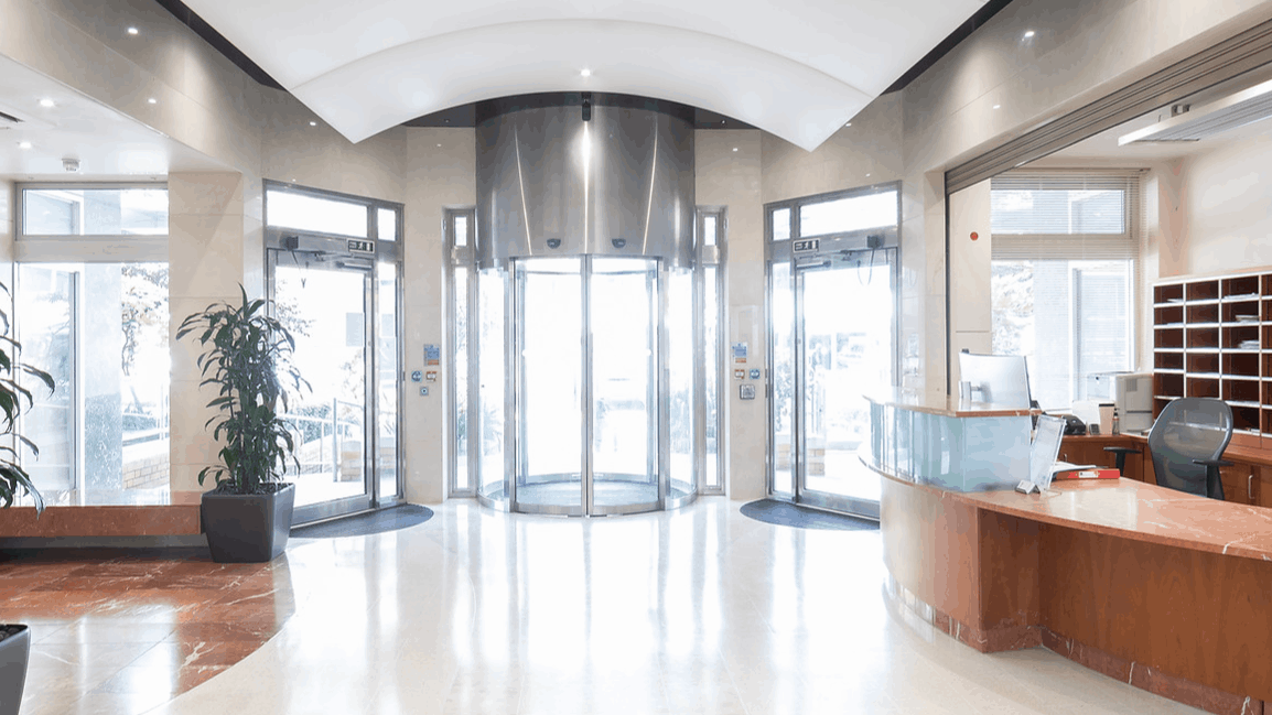 A large lobby with a revolving door and a reception desk.