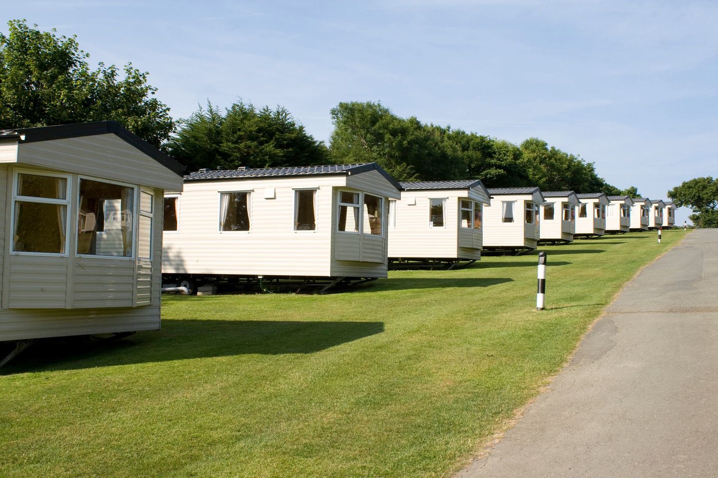 A row of mobile homes are parked on the side of a road