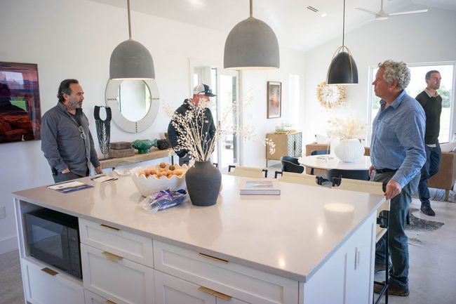 A group of men are standing around a large island in a kitchen in Roundtop, Texas, and looking at the power of Solar Power.