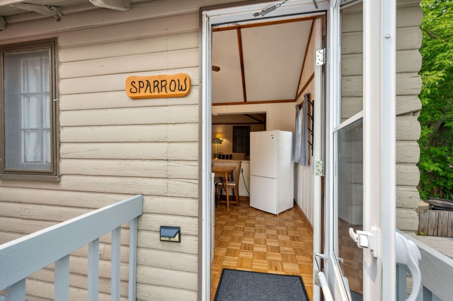 Exterior view of a small cabin, doorway open. 