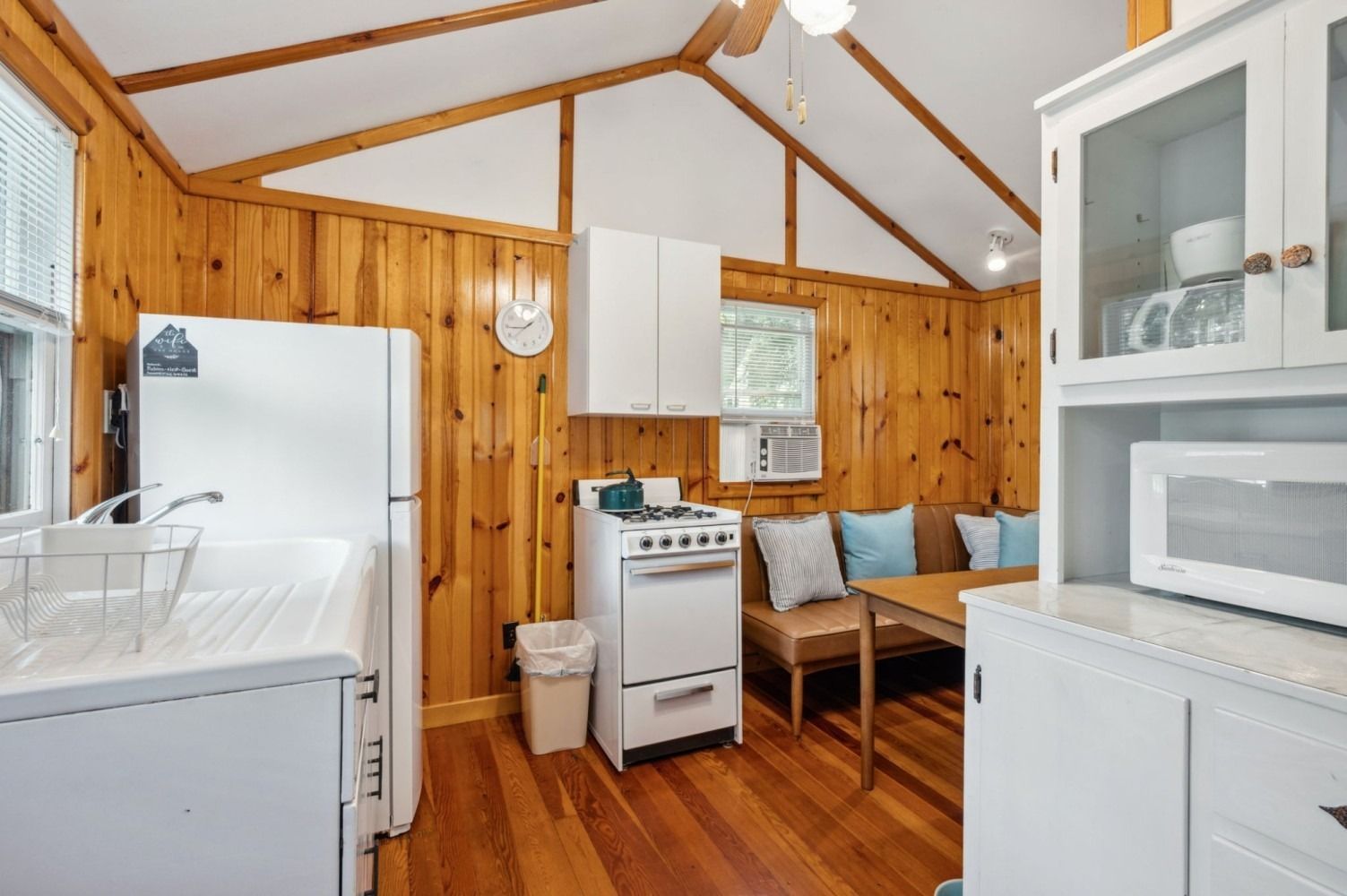 Small cabin kitchen with wood paneling, white appliances, and a small dining area.