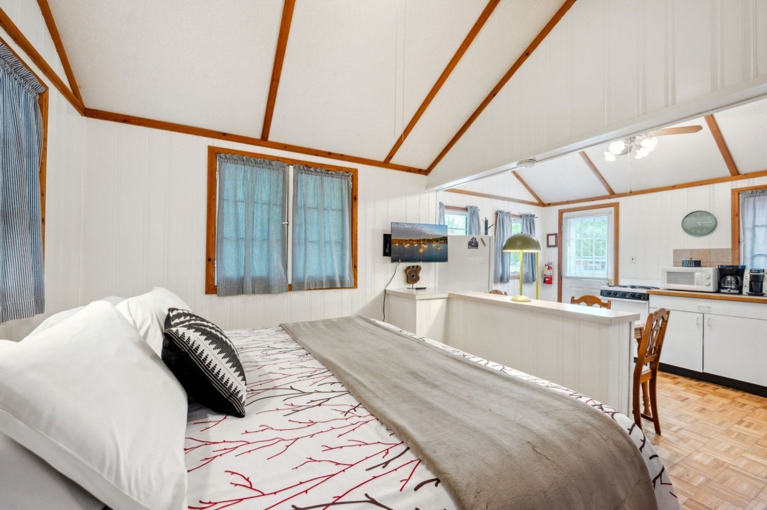 Bedroom and kitchenette in a cabin with a bed, TV, and basic kitchen.