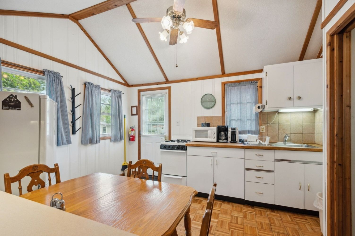 Small kitchen and dining area with wooden table, white cabinets, and a ceiling fan.