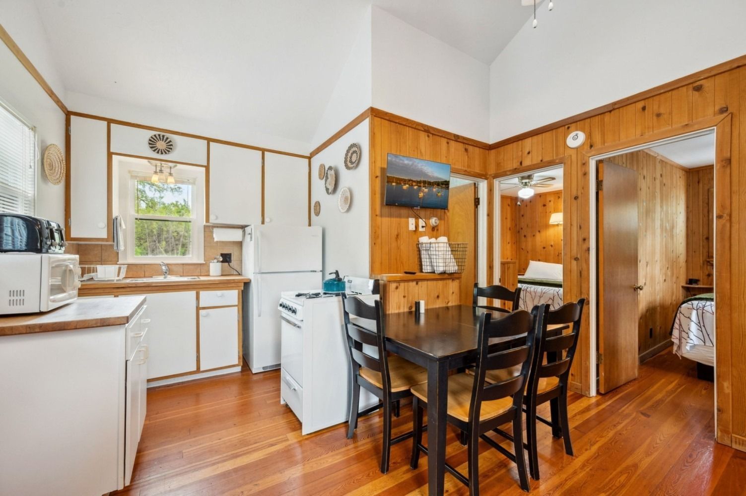 Kitchen with white cabinets, wooden walls, dining table, and two doorways.