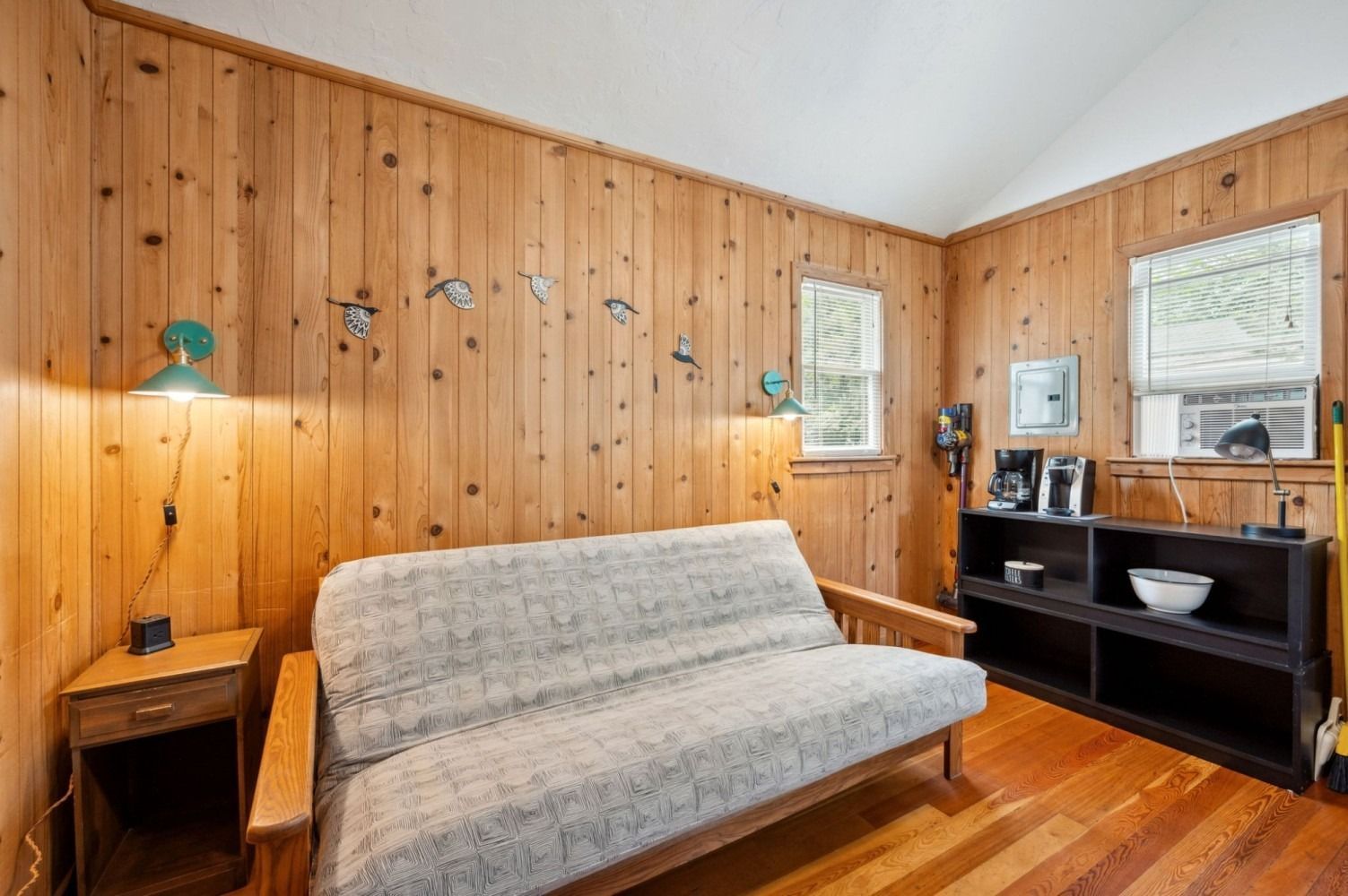 Living room with wood paneling, futon, and small windows.