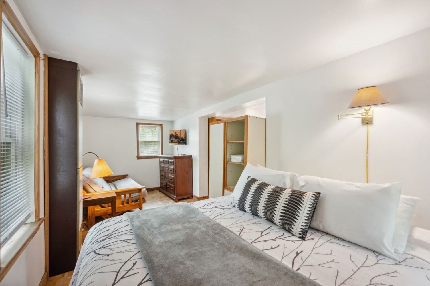 Bedroom with bed, futon, wooden furniture, and a window.