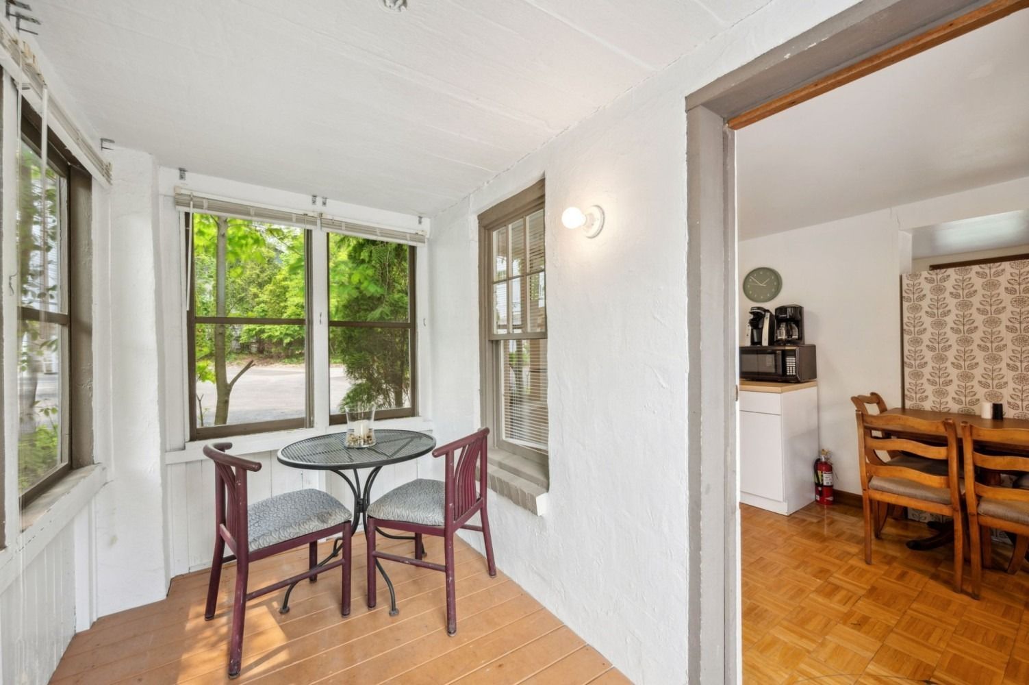 Small sunroom with a table and chairs, connected to a dining area.
