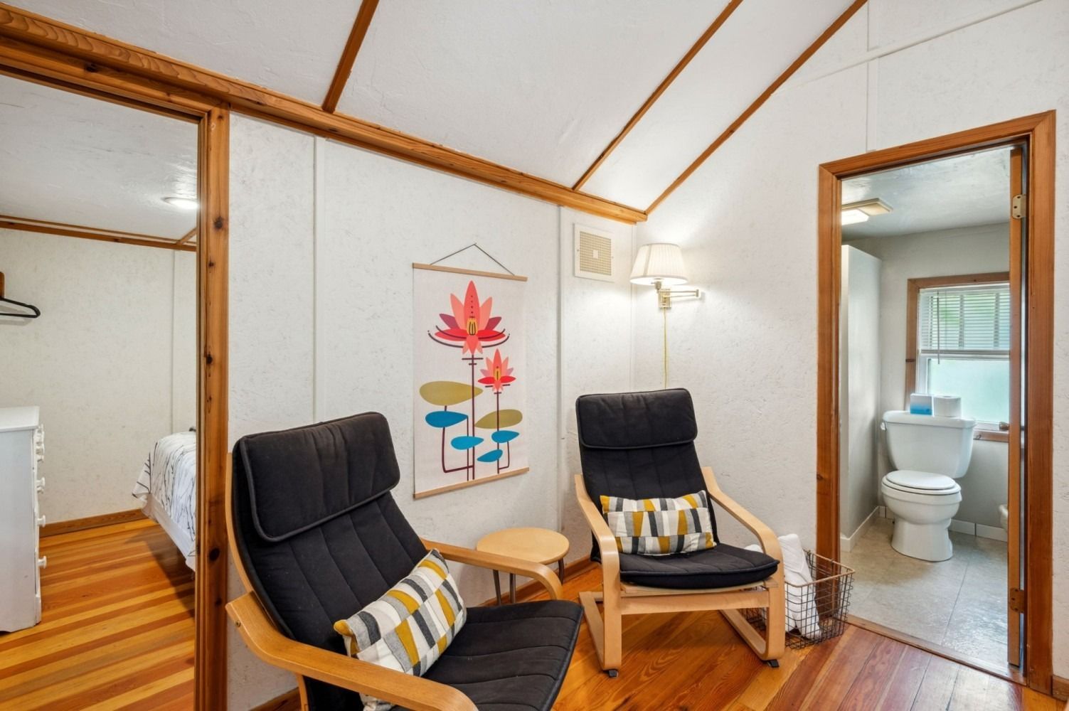 Two black chairs face each other in a room with wood floors and three doorways.