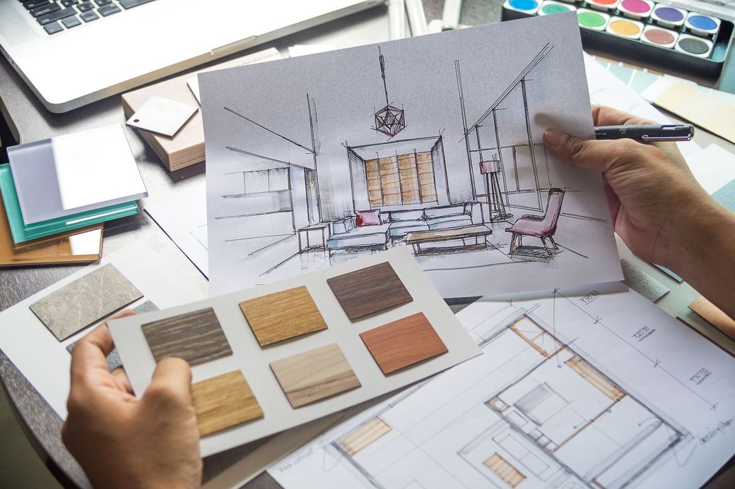 A person is holding a drawing of a living room and a palette of wood samples.