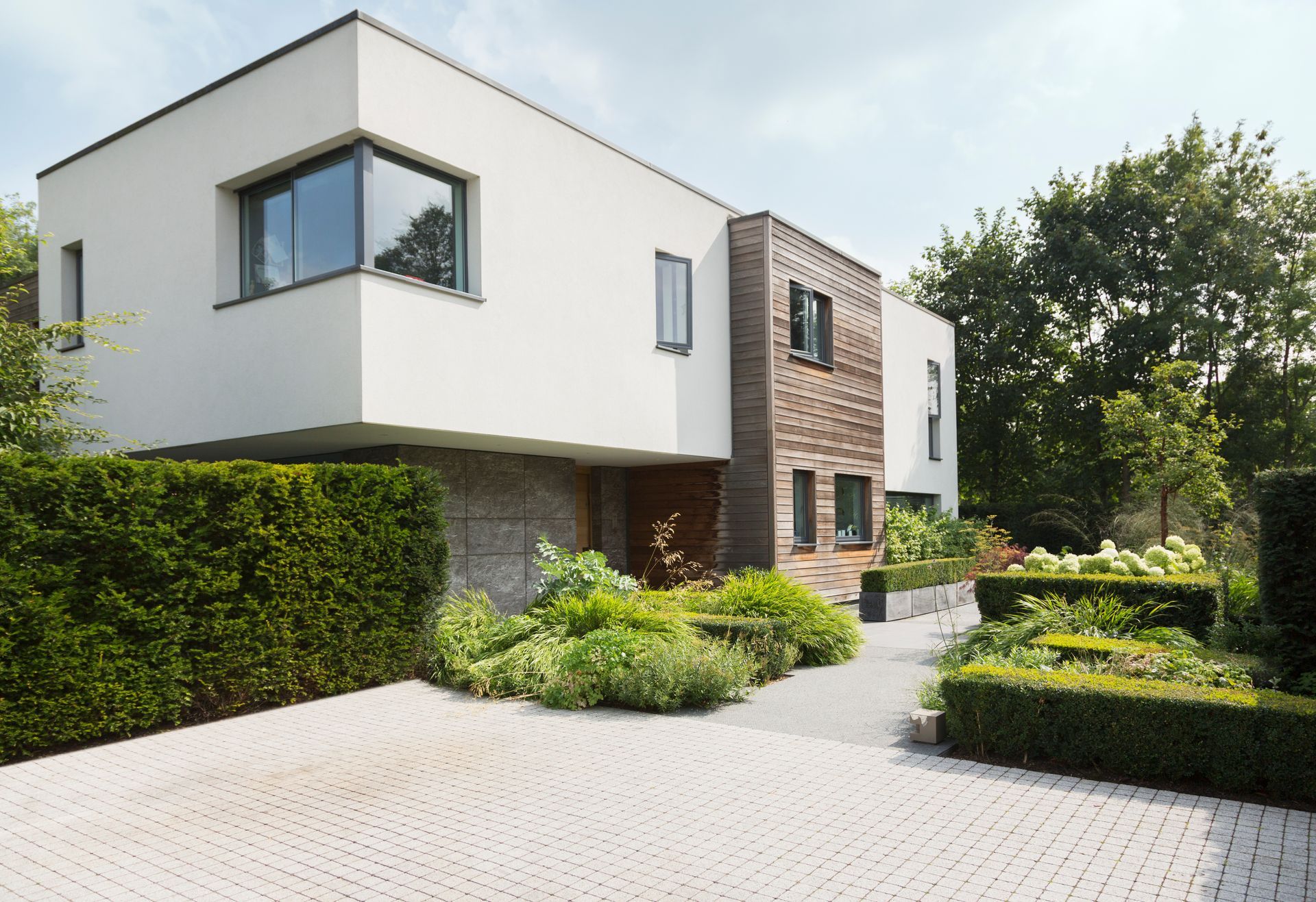 A large white house with a brick wall and a driveway