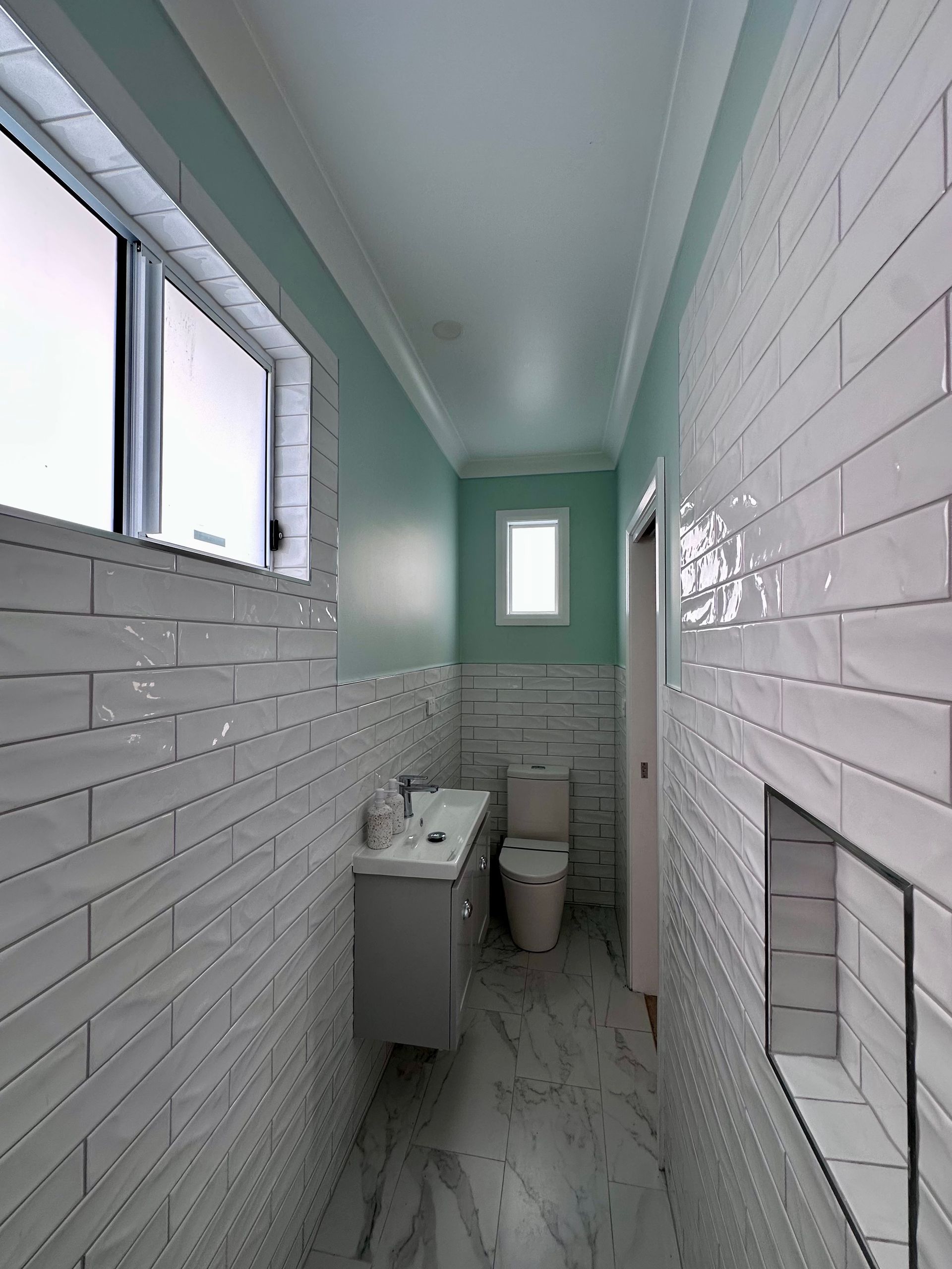 A bathroom with a toilet , sink , and window.