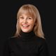 The woman is wearing a black turtleneck and smiling.
