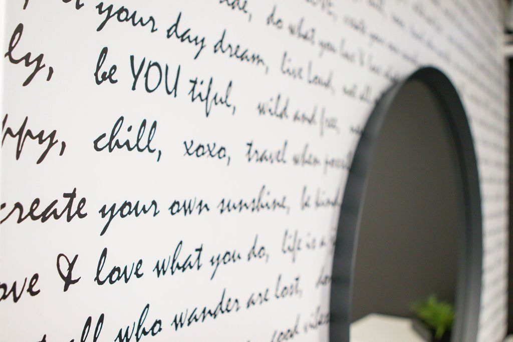 Wall with motivational handwriting in black. A round mirror is on the right.
