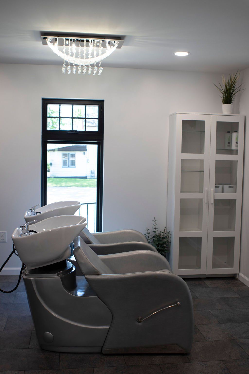 Hair salon with three wash stations, cabinet, and window looking outside.