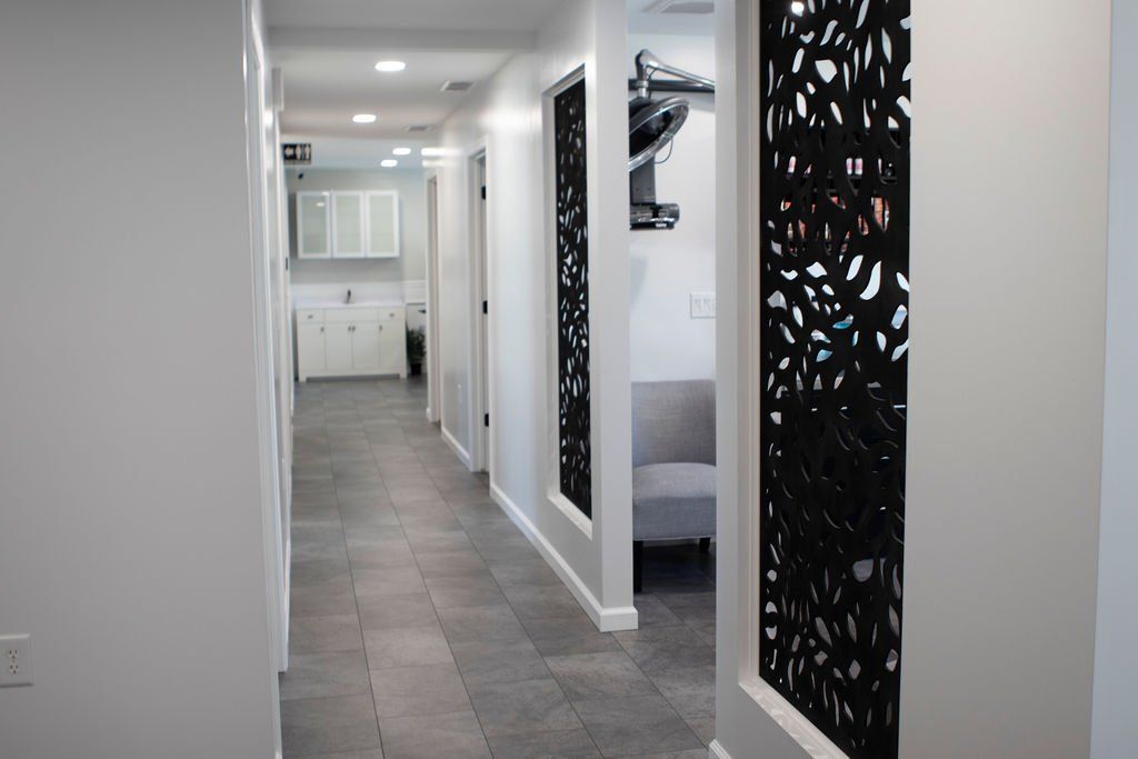 Long, modern hallway with gray tile floor, white walls, and decorative black panels.