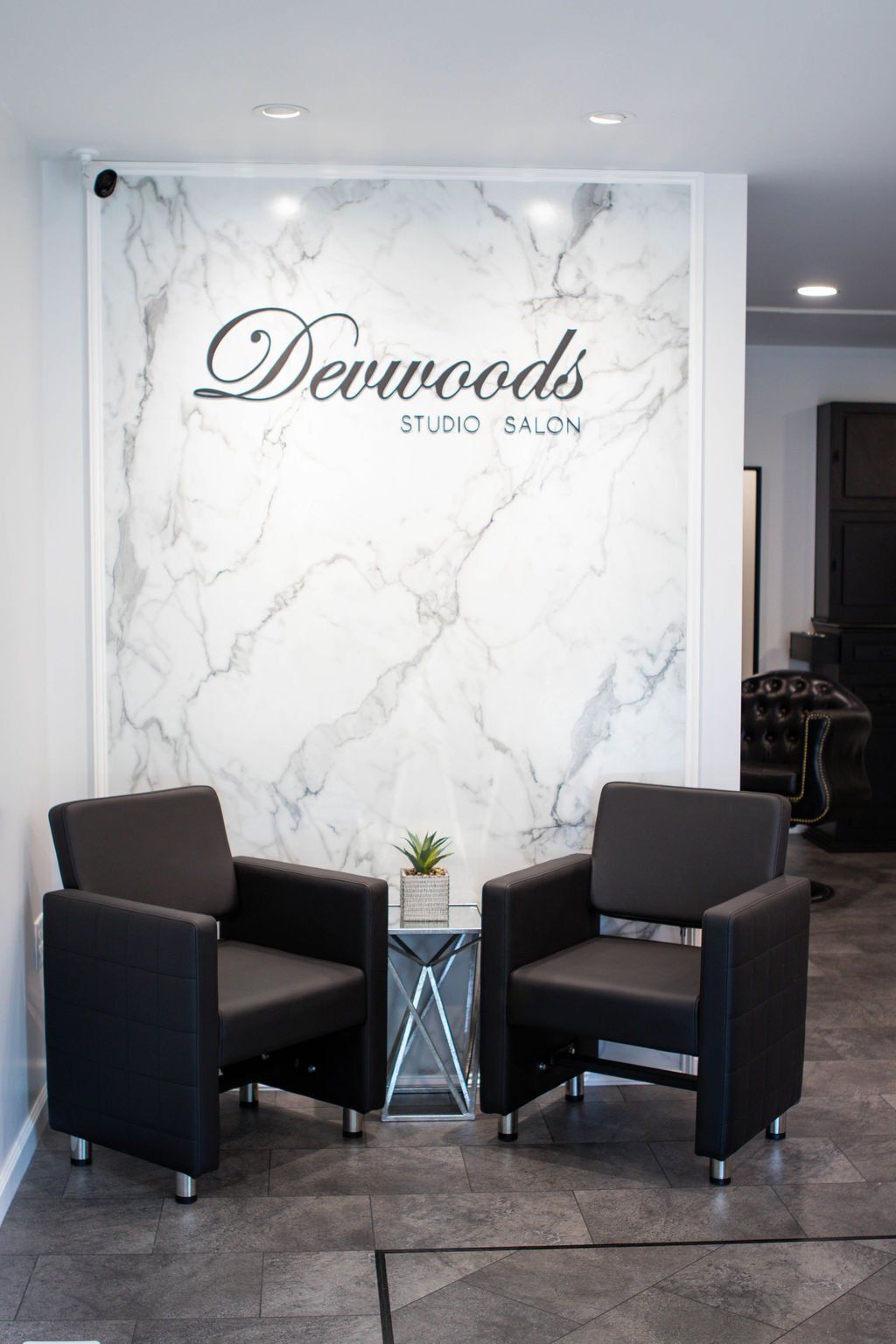 Two black chairs face a marble wall with 