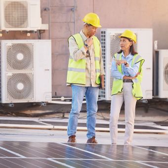A man and a woman are standing near a group of ac units