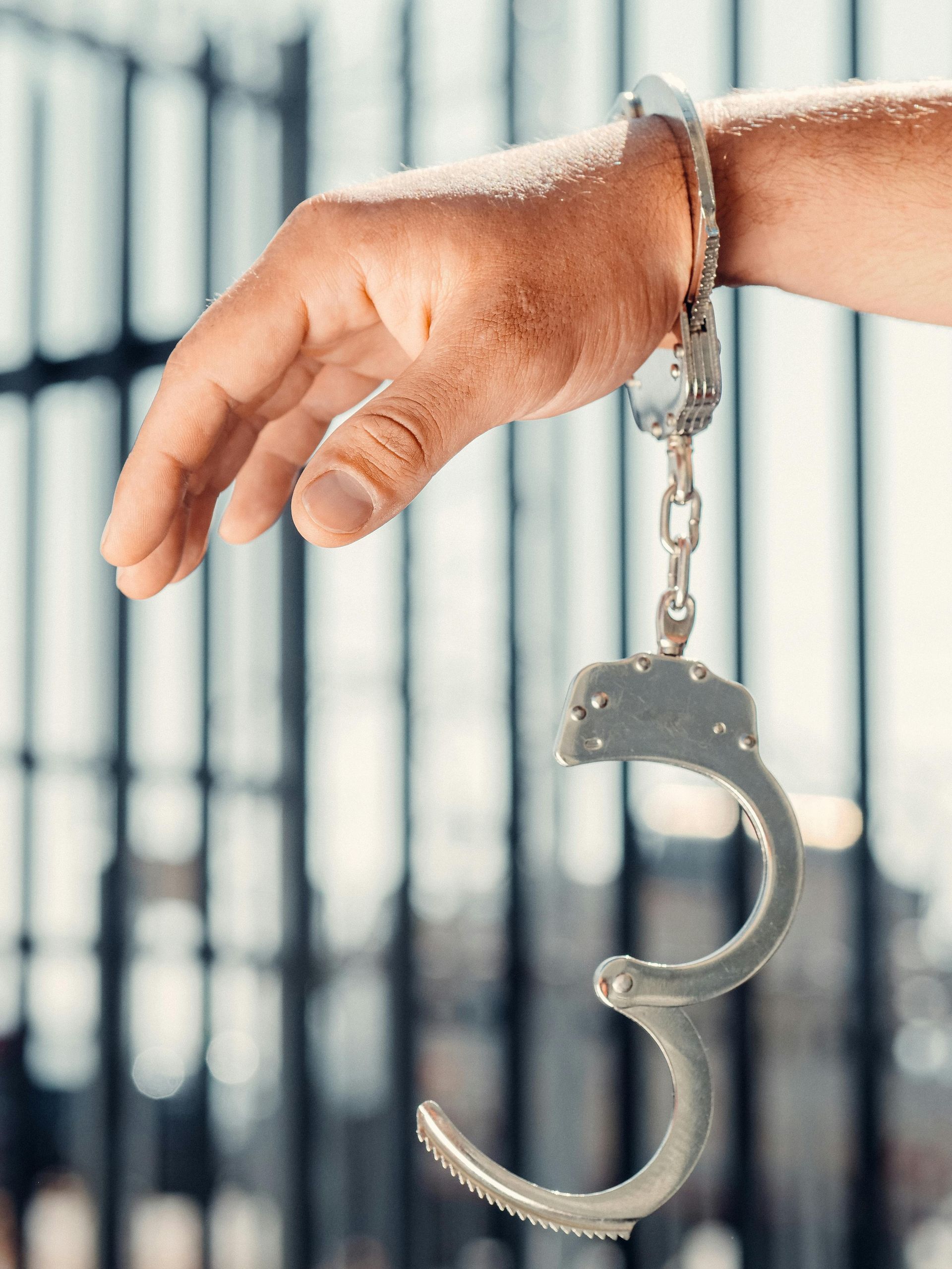 A person is holding a pair of handcuffs on their wrist.