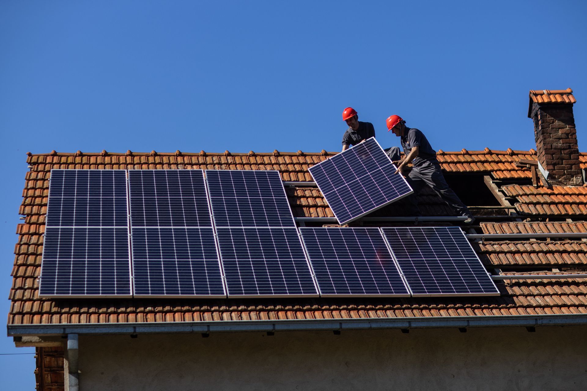 Two solar panel installers mounting solar panels on roof of house. Two solar panel installers mounting solar panels on roof of house.