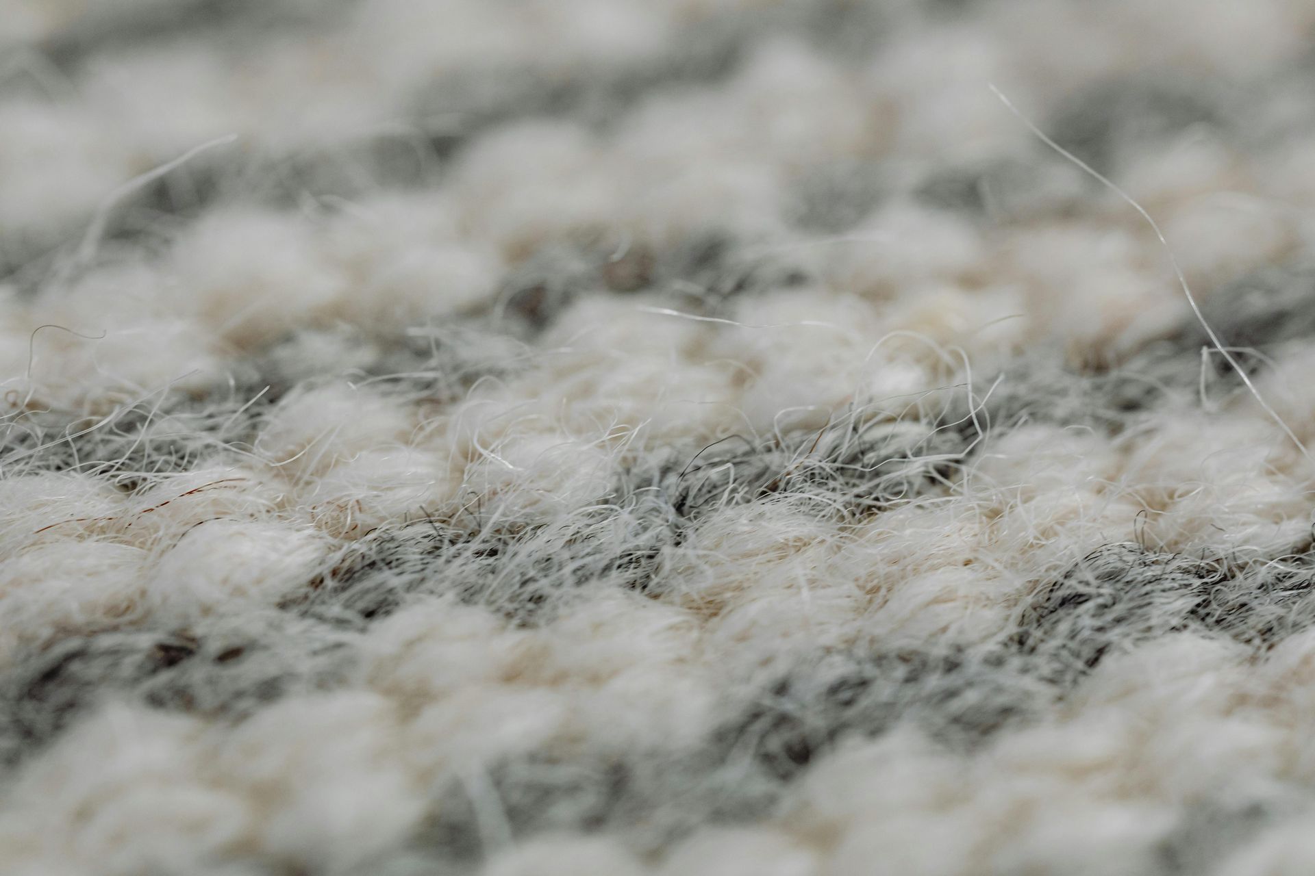 Close-up view of textured carpet with alternating light beige and gray stripes.
