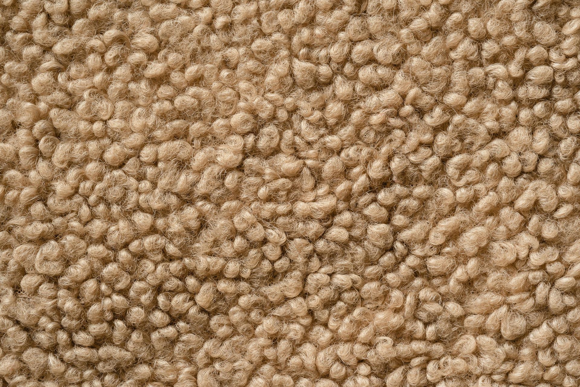 Close-up of tan, textured fabric, resembling sheepskin or faux fur.