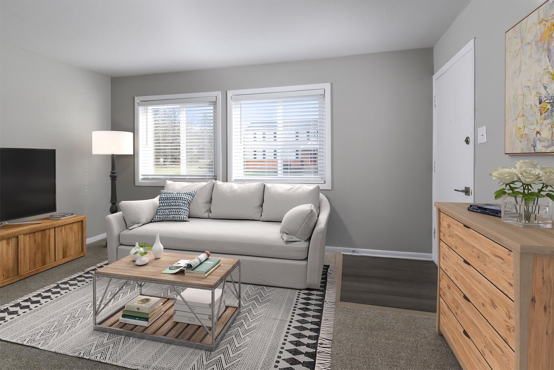 Living room with gray walls, a light sofa, coffee table, TV on a wooden console, and a dresser.