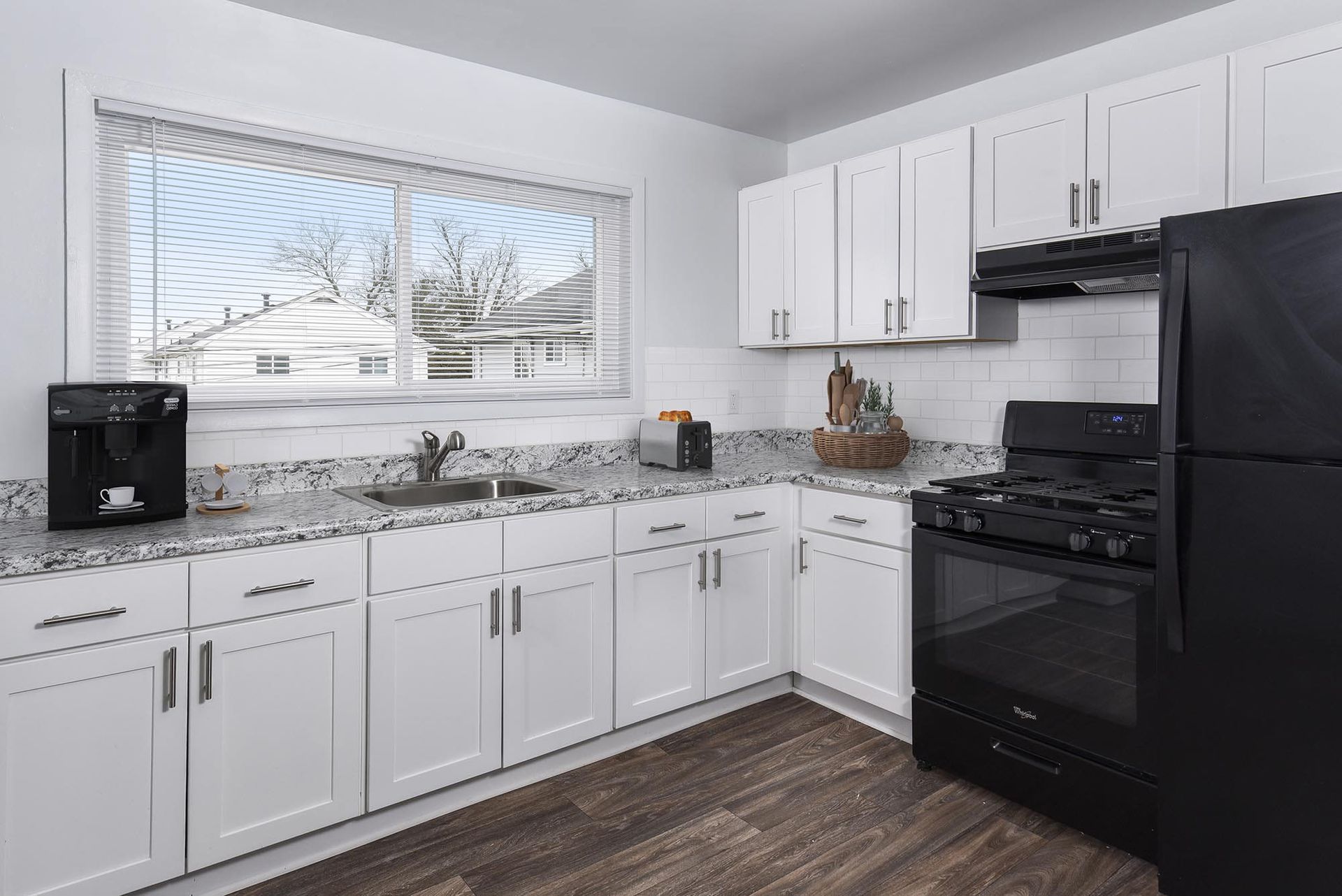 Bright, modern kitchen with white cabinets, granite countertops, and black appliances.