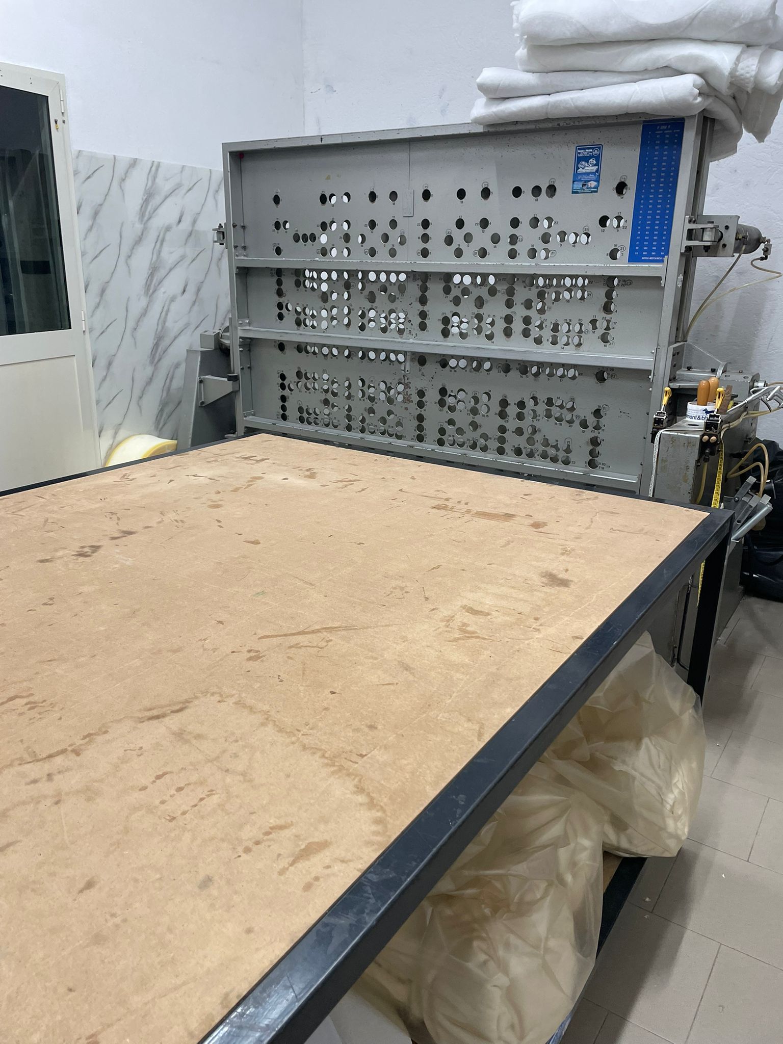 Un grande tavolo da taglio o da stampa industriale con superficie piana, dotato di un pannello di controllo metallico con pulsanti retroilluminati.