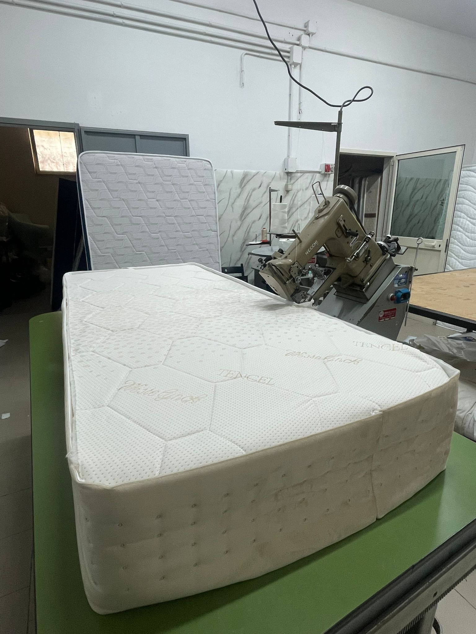 Un materasso cucito da una macchina da cucire industriale in un laboratorio di fabbrica.