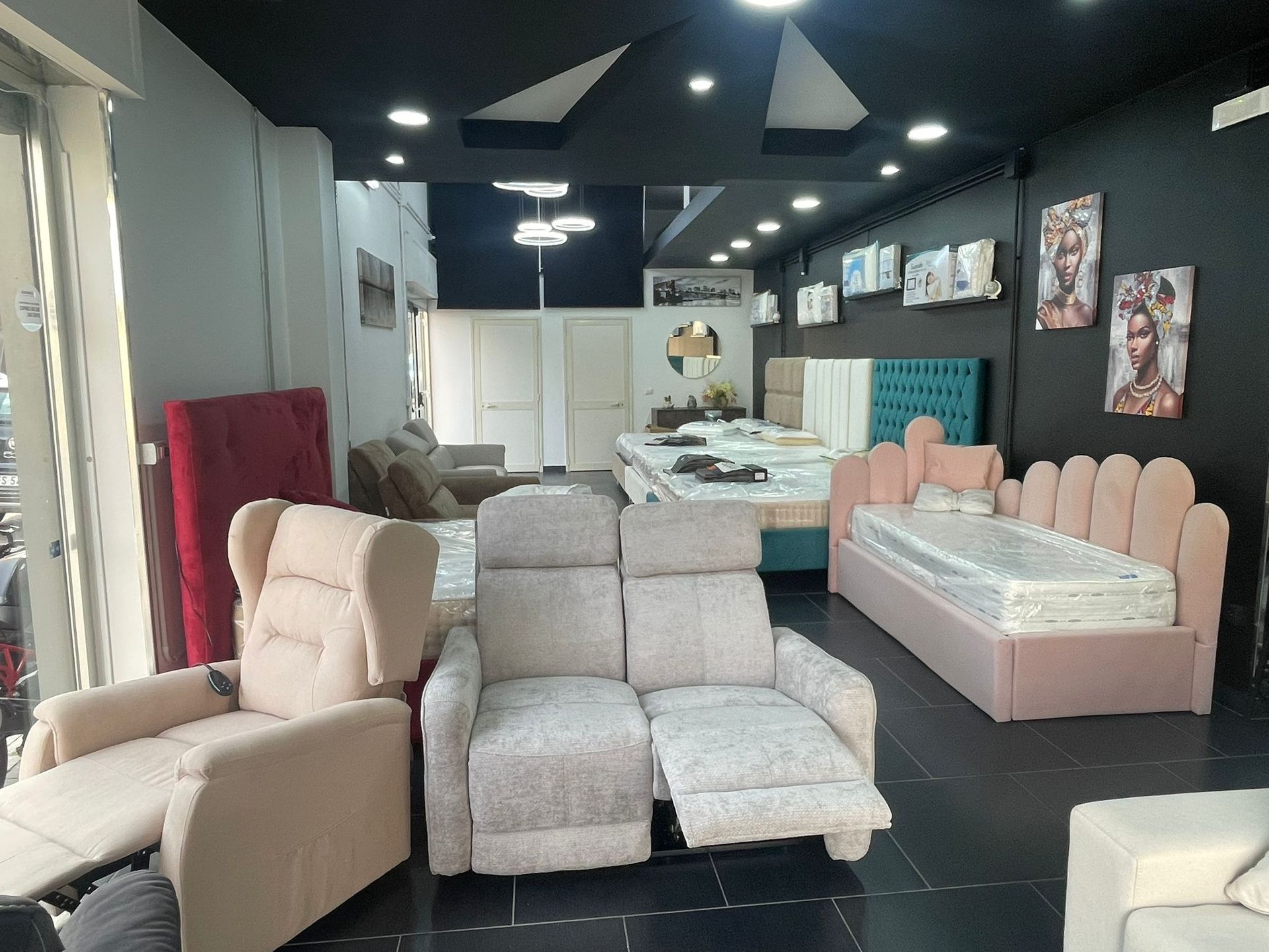 Esposizione in showroom con una poltrona reclinabile color crema, un divano a due posti con motivi chiari e un letto imbottito color rosa cipria.