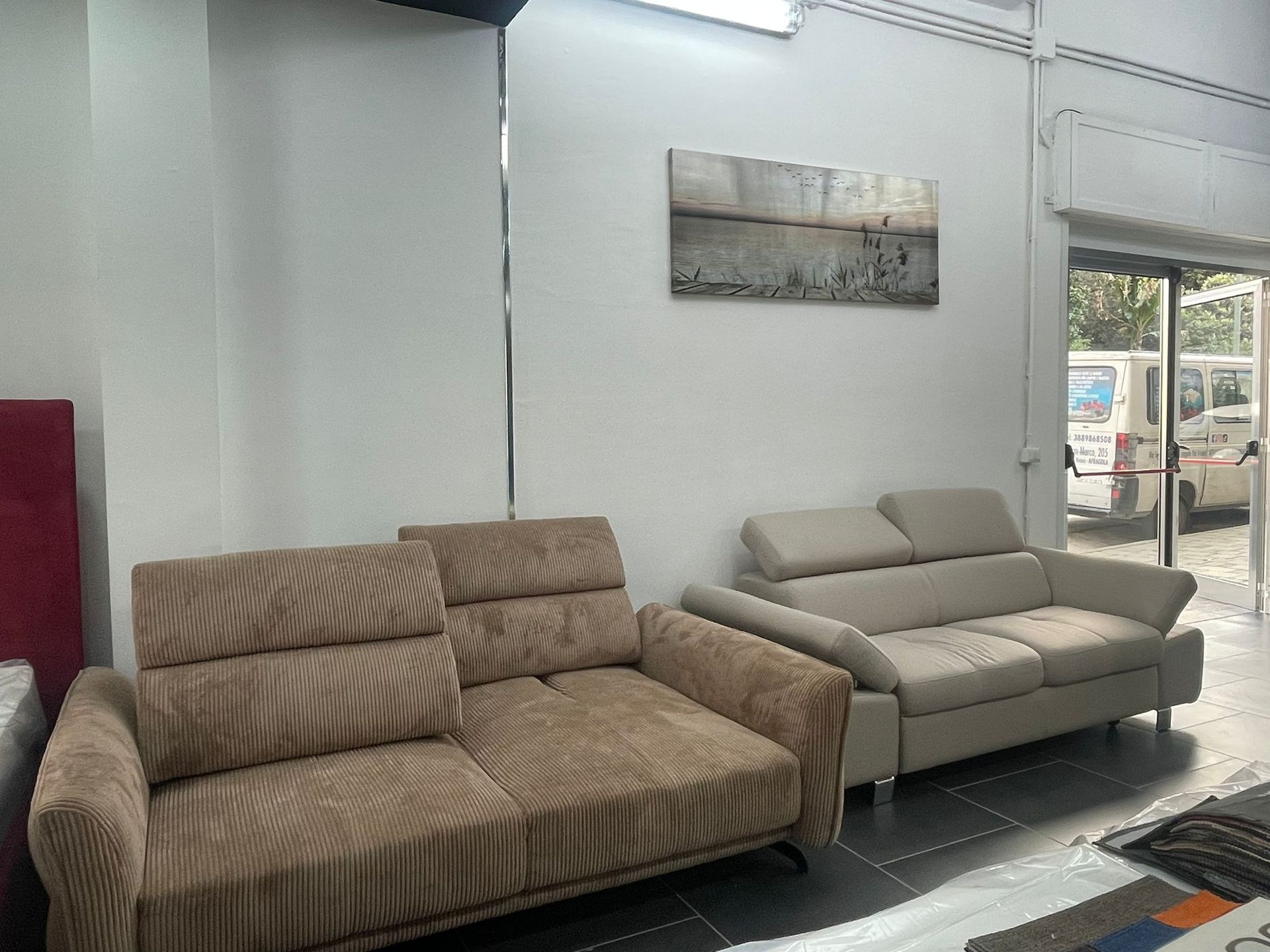 Un divano in velluto a coste marrone e un divano beige chiaro sono posizionati in una stanza luminosa con un quadro alla parete.