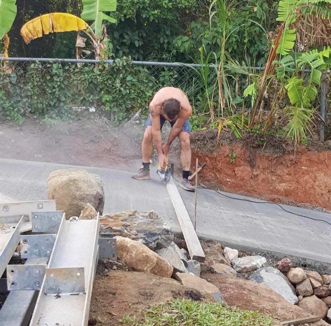A Man Is Raking Concrete on A Construction Site — Bunker FNQ in Port Douglas, QLD