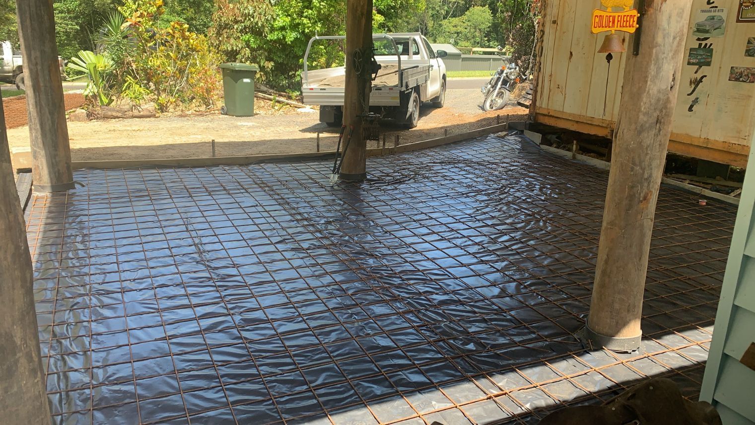 A Man Is Pouring Concrete Into a Hole with A Shovel — Bunker FNQ in Cooktown, QLD