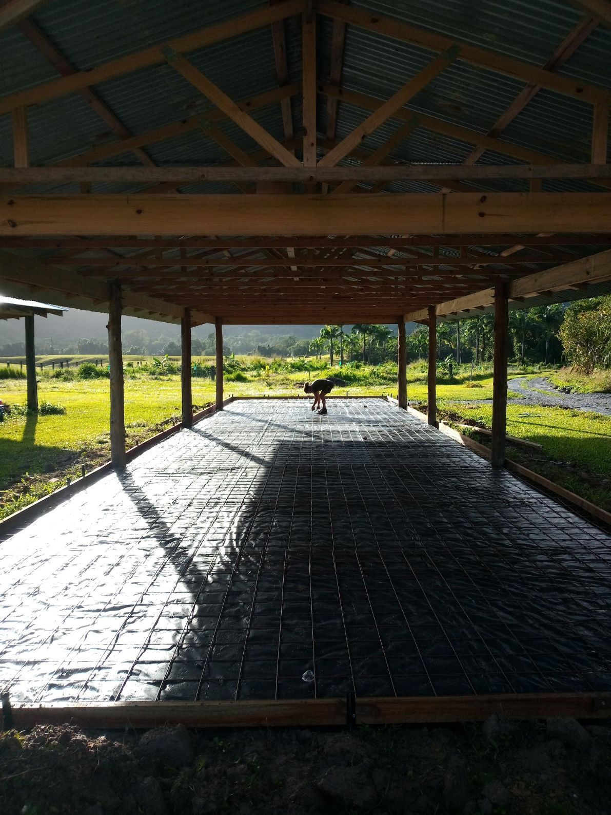 A Man Wearing a Hard Hat Is Using a Hose to Pump Concrete — Bunker FNQ in Cooktown, QLD