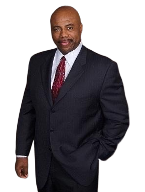 Man in a dark suit, white shirt, and red tie, standing with one hand in his pocket on a white background.
