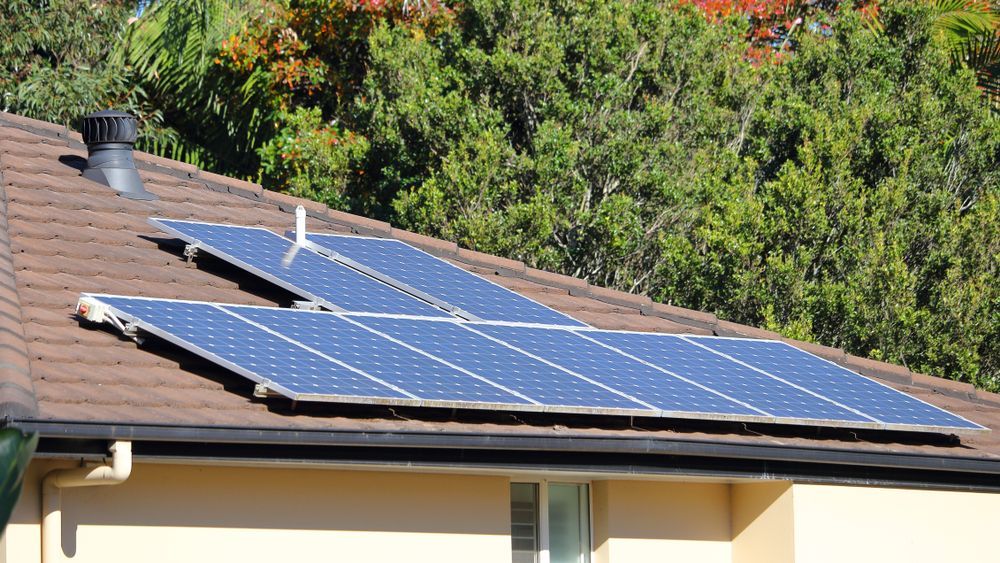Two Men Are Looking at a Tablet in Front of a Solar Panel — SEP Electrical Pty Ltd in Wollongong, NSW