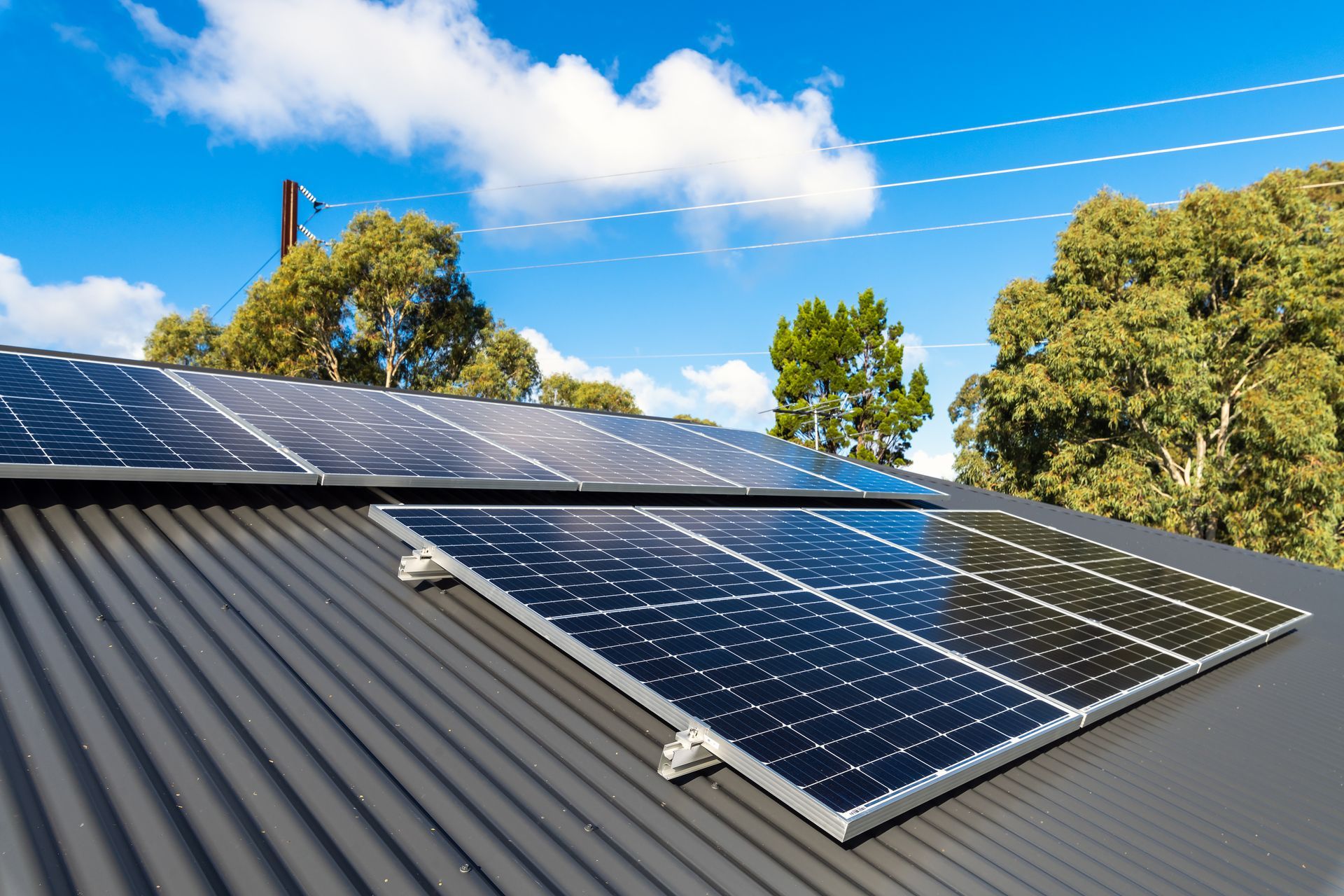 A Man is Installing Solar Panels on a Roof — SEP Electrical Pty Ltd in Towradgi, NSW