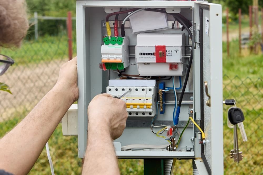 A Man is Working on an Electrical Box With a Screwdriver — SEP Electrical Pty Ltd in Dapto, NSW